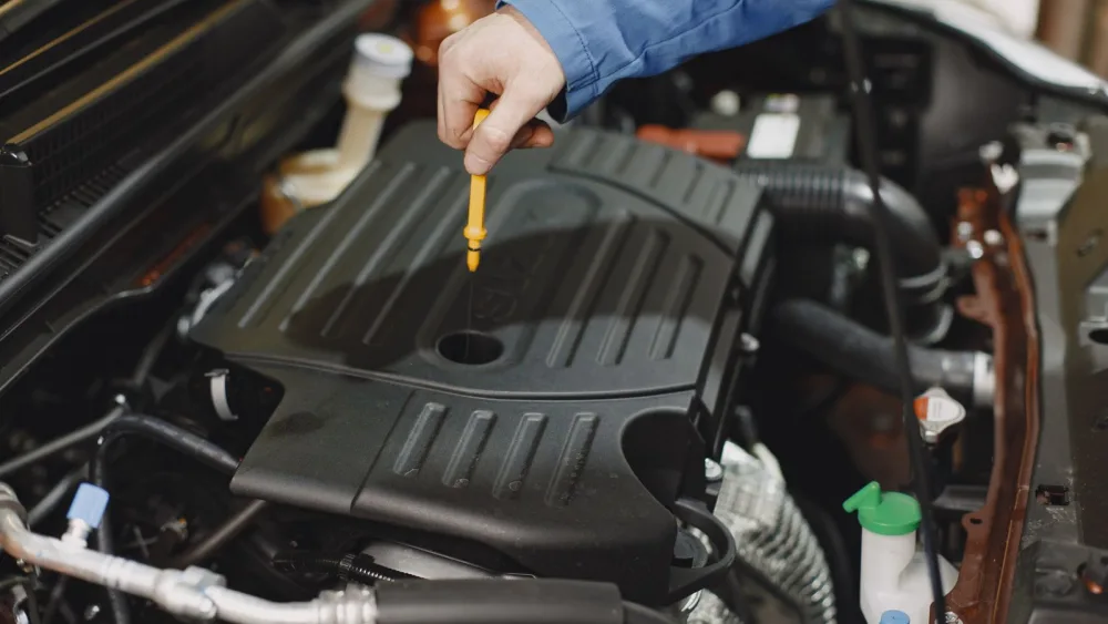Mecânico verificando o nível de óleo do motor com a vareta
